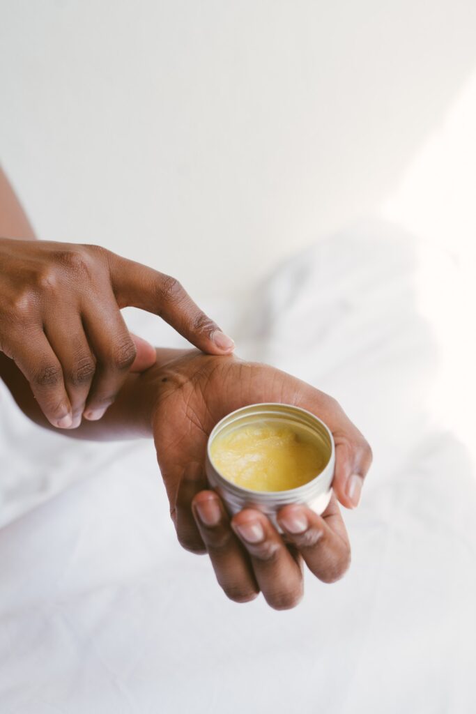 upclose graphic of a black woman applying salve to her hands while holding a tin can of an ointment.  in a blog about overworked moms 