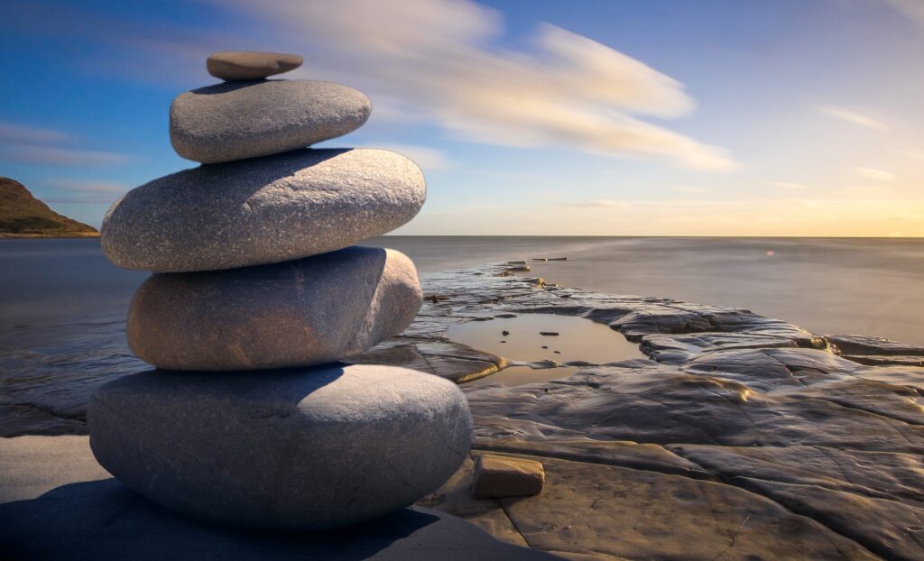 photo of rocks piled up on a ledge overlooking the shoreline during dawn or dusk