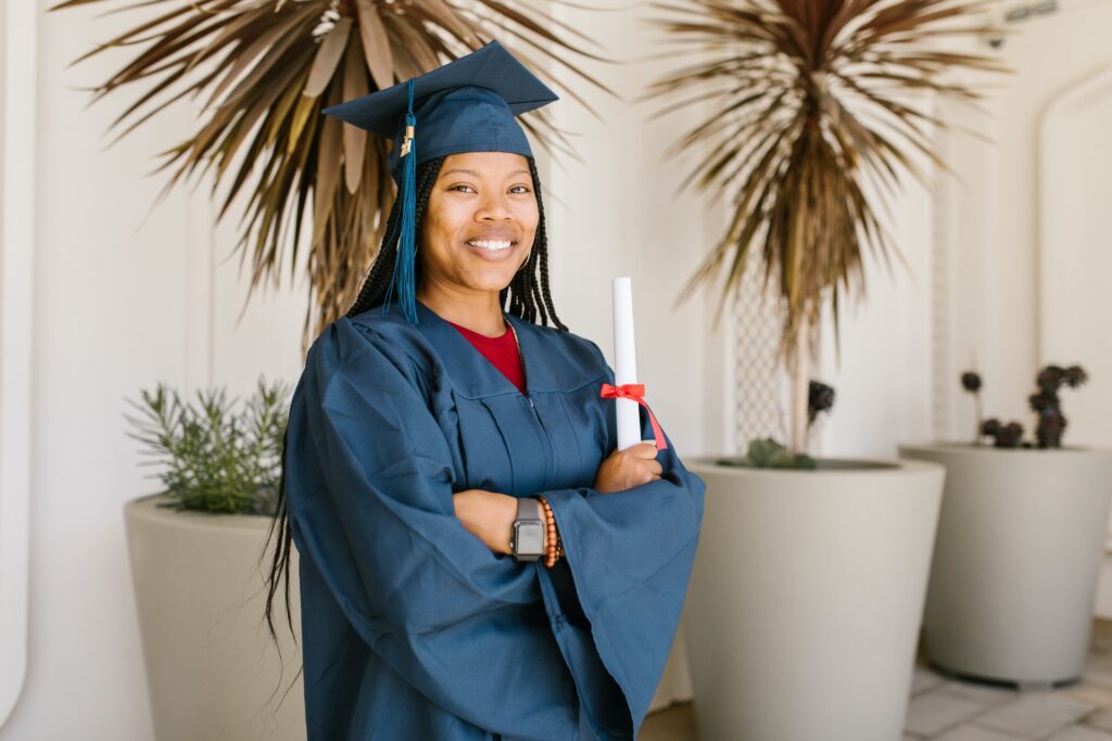 recent graduate in a blue cap and gown holding diploma on graduation day