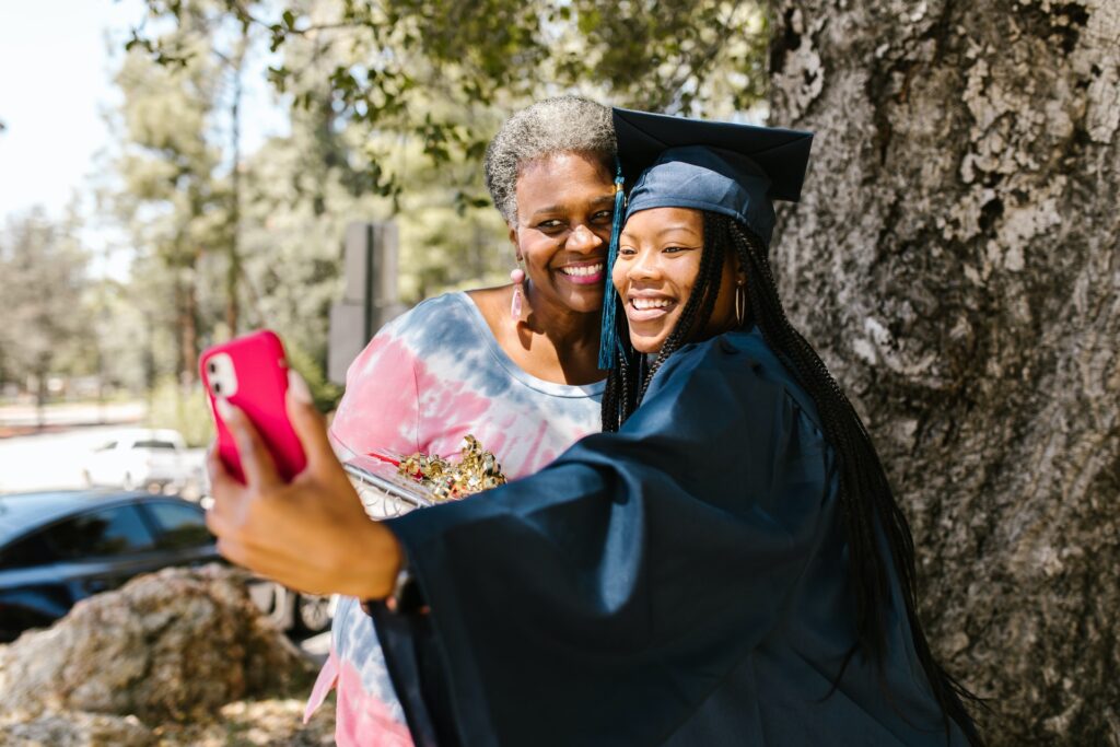 mom taking photo with daughter in cap and gown on graduation day
