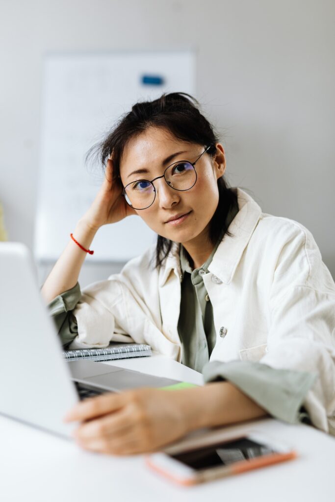 photo of a woman looking at a camera with her laptop in front of her, her hand on her head in blog article about the importance of employers taking care of their employees in order to survive post pandemic shortage