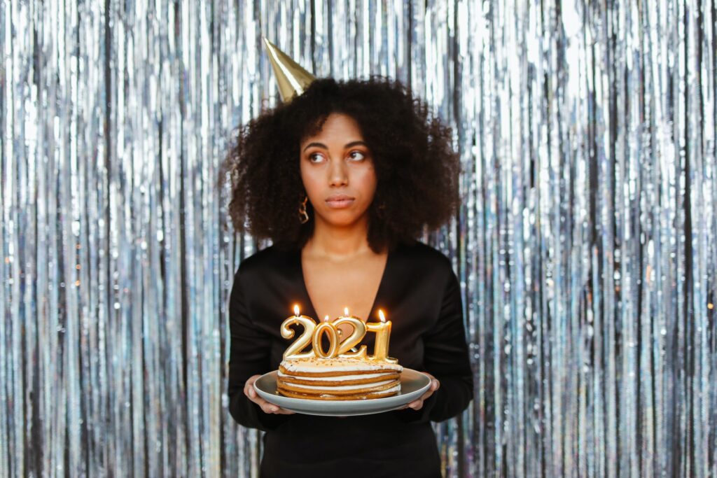Image of a a girl wearing a hat and a cake with 2021 Candles 